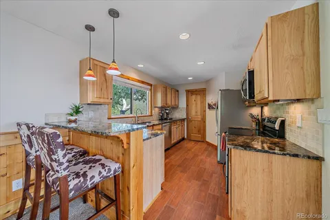 a kitchen with granite countertop a stove a sink and a refrigerator