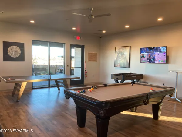 a room with furniture pool table wooden floor and windows