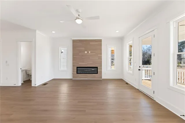 an empty room with wooden floor fireplace and windows