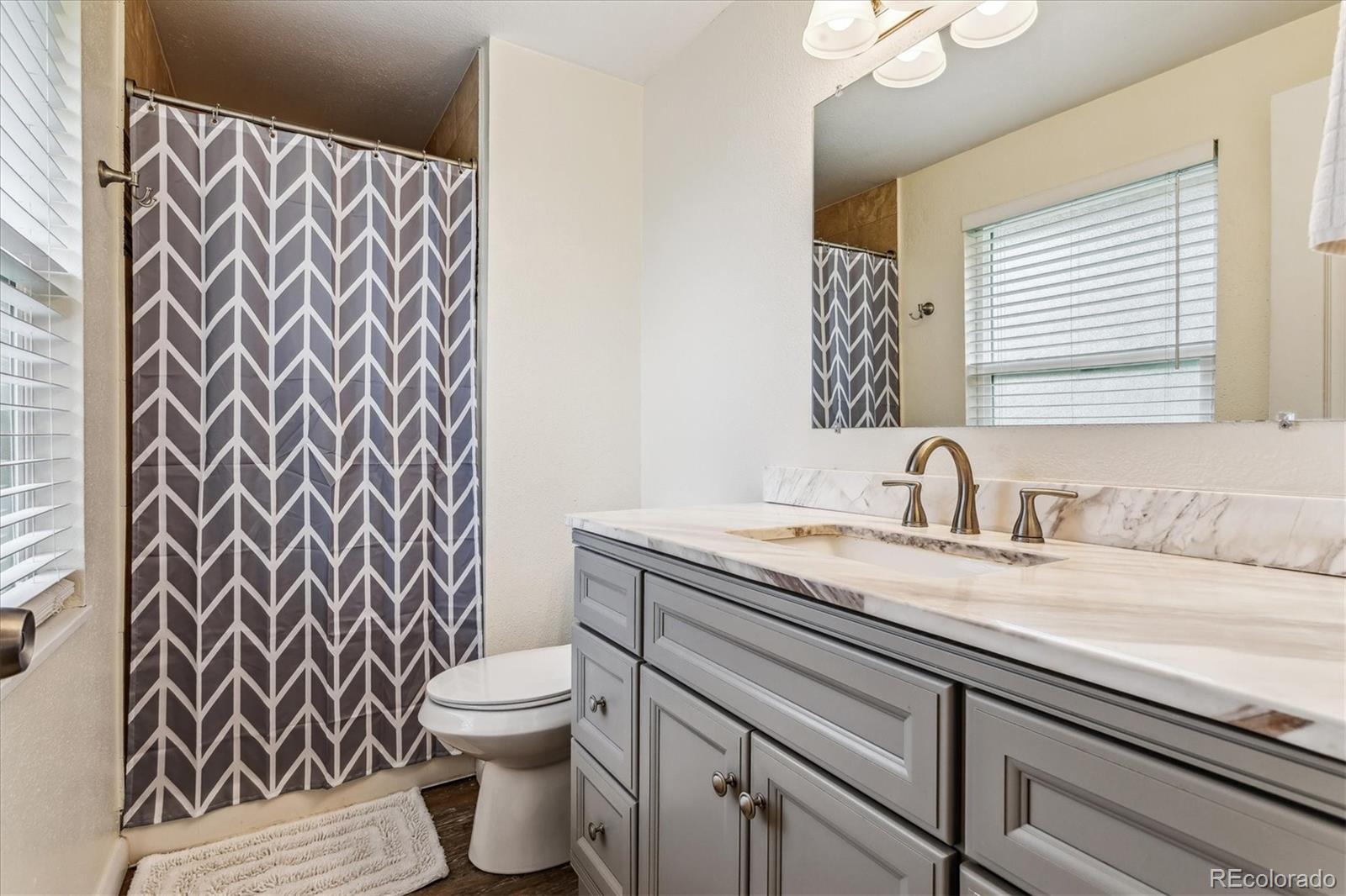 4844 Scranton Court Denver, CO 80239 - Photo 13 of 25 a bathroom with a granite countertop toilet sink and mirror