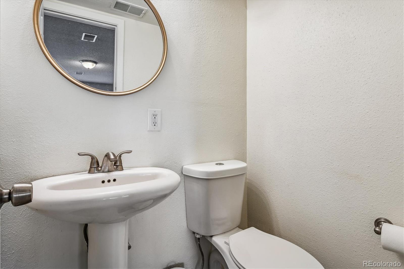 4844 Scranton Court Denver, CO 80239 - Photo 16 of 25 a bathroom with a toilet a sink and mirror