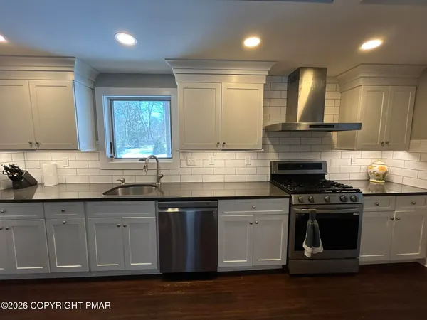 a kitchen with stainless steel appliances granite countertop a stove a sink and a microwave