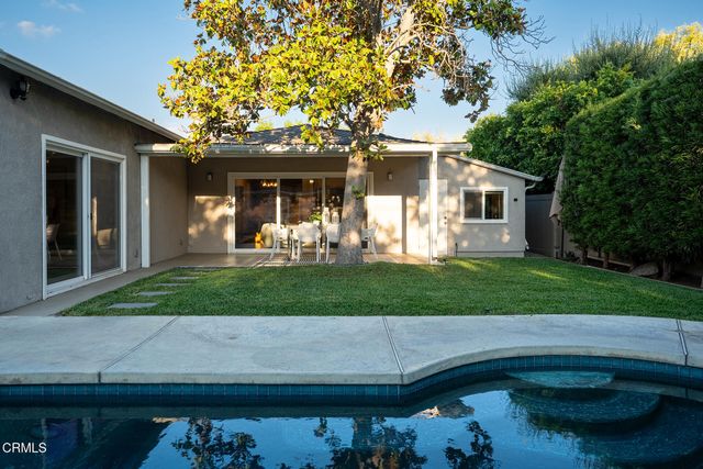 a view of a back yard of the house with a large tree