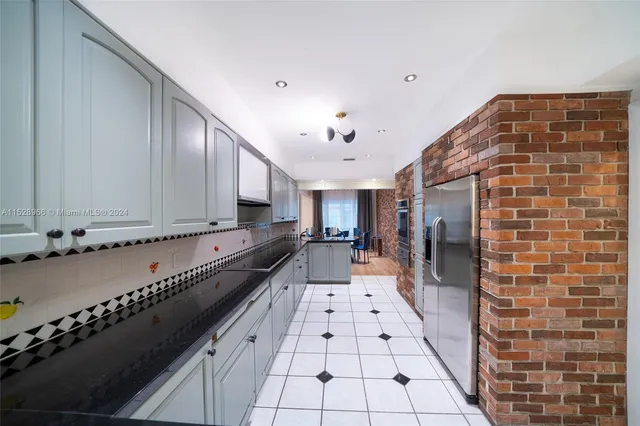 a large white kitchen with granite countertop a sink and a black white refrigerator