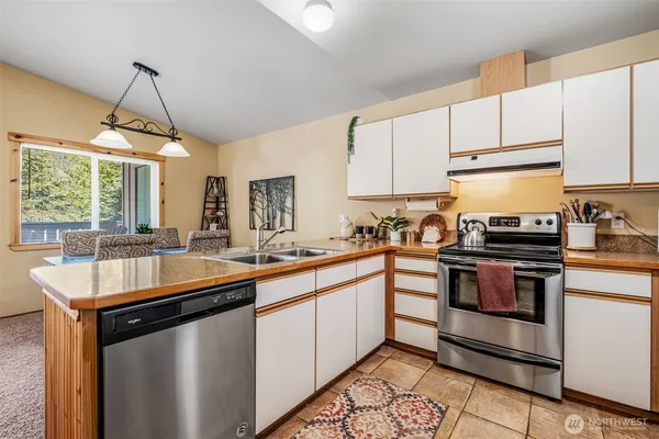 a kitchen with stainless steel appliances a sink a stove a refrigerator and cabinets