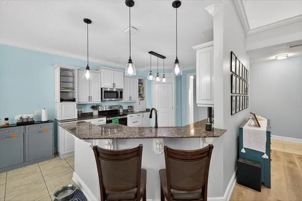 a kitchen with stainless steel appliances granite countertop a sink a stove a refrigerator cabinets and chairs