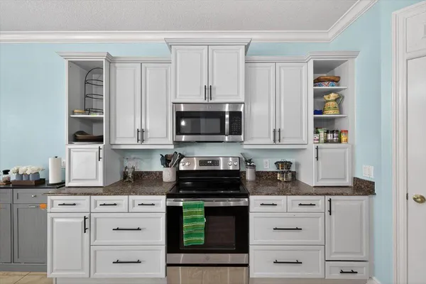 a kitchen with stainless steel appliances granite countertop a sink a stove and cabinets