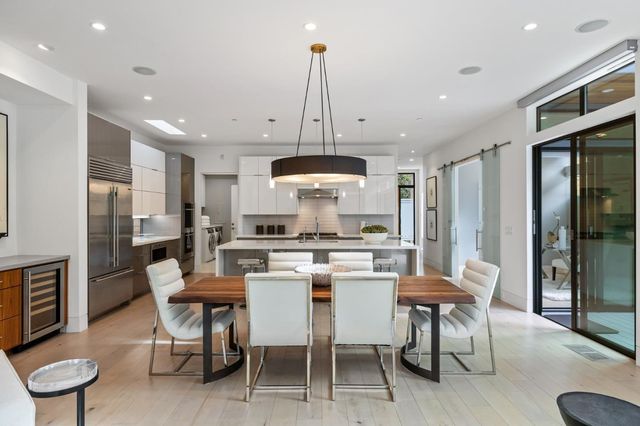 a dining room with stainless steel appliances kitchen island granite countertop a dining table chairs and a refrigerator