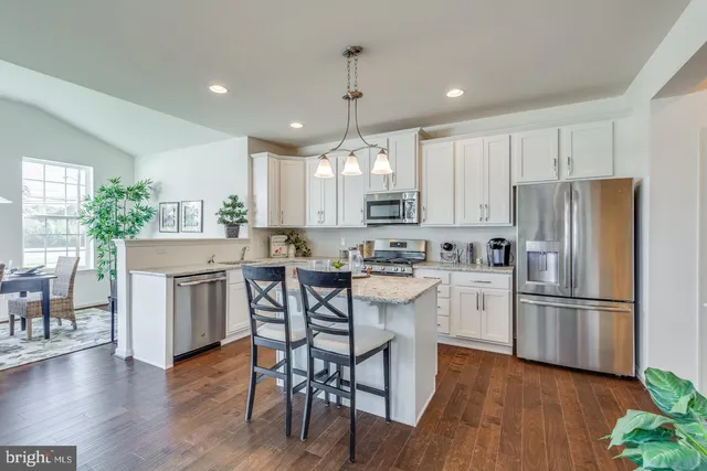 a kitchen with refrigerator a stove and wooden floor