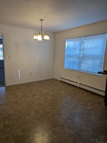 an empty room with chandelier fan and windows
