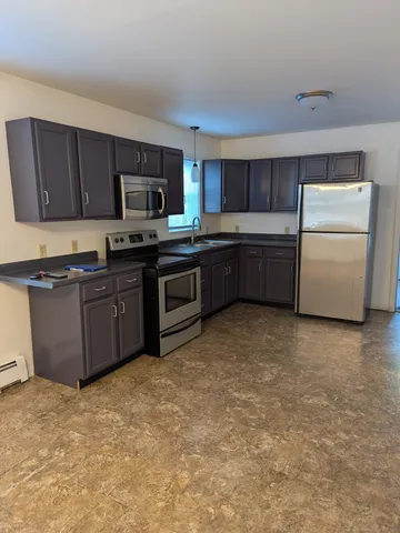 a large kitchen with stainless steel appliances granite countertop a stove a sink dishwasher and a refrigerator