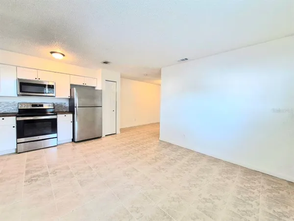 a view of a kitchen with a sink stove cabinets and stainless steel appliances