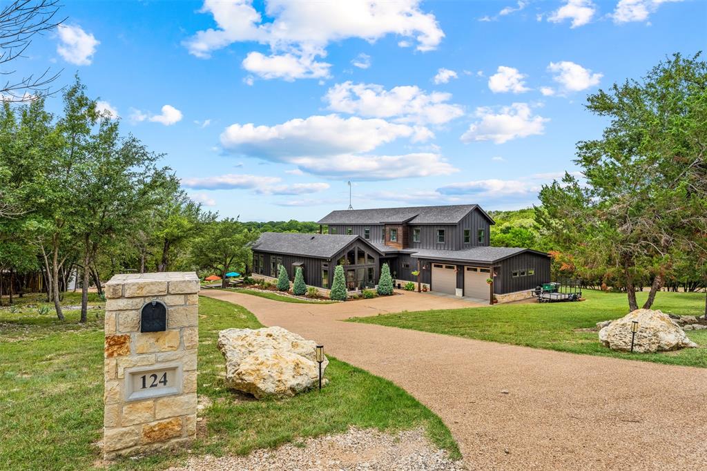 124 Bluffview Circle China Spring, TX 76633 - Photo 2 of 40 Gravel driveway extending to a contemporary two-story home featuring dark vertical siding, a multi-car garage, and a stone mailbox post