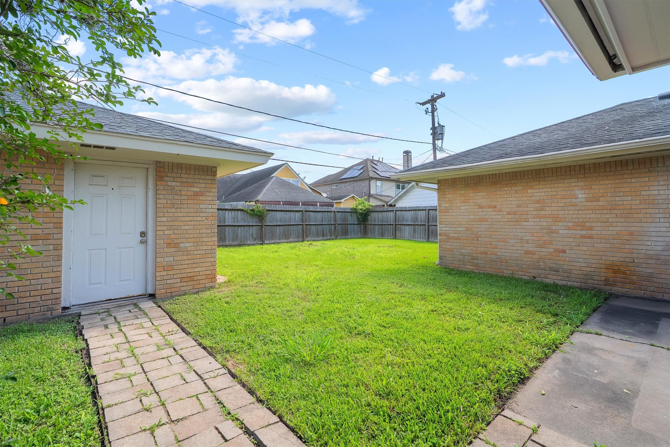 3331 Arbor Street Houston, TX 77004 - Photo 27 of 30 This photo showcases the large backyard with a well-maintained lawn, bordered by a wooden fence for privacy. It features a path leading to the garage.