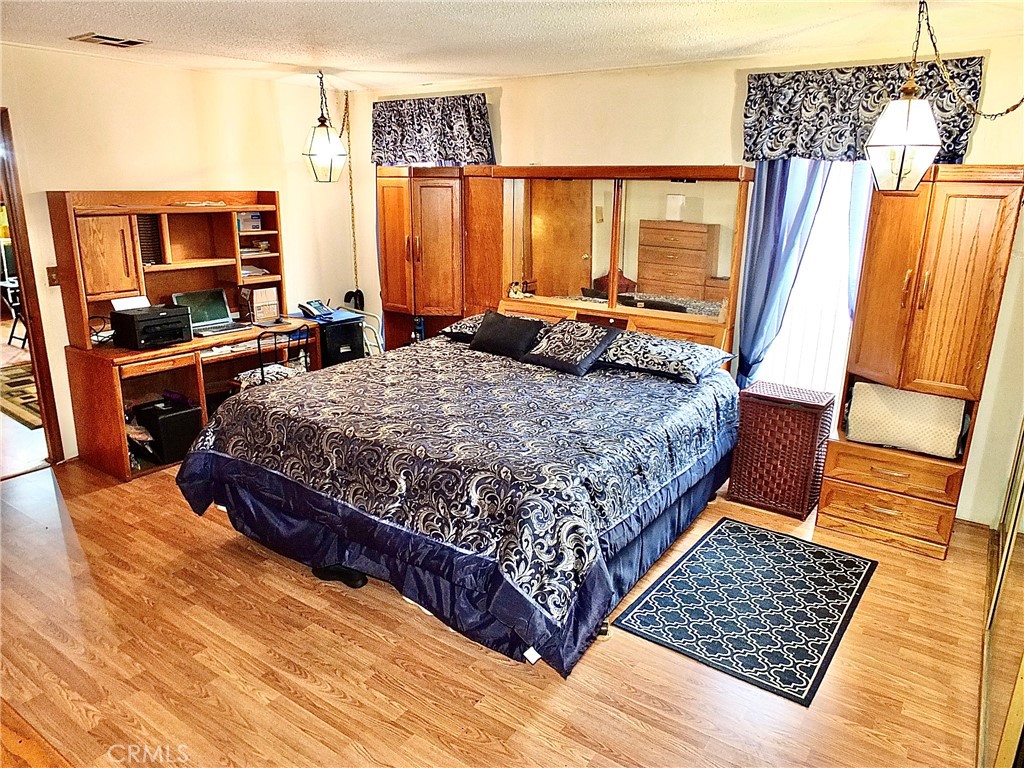 2601 East Victoria Street, Unit 439 Rancho Dominguez, CA 90220 - Photo 28 of 32 a bedroom with a bed and wooden floor