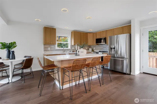 a kitchen with stainless steel appliances a dining table chairs and wooden floor