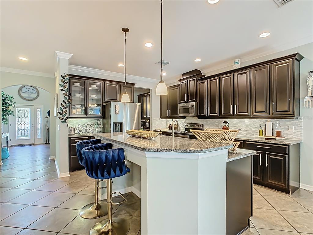 168 Magneta Loop Auburndale, FL 33823 - Photo 13 of 75 a kitchen with stainless steel appliances granite countertop a sink a stove a refrigerator and chairs