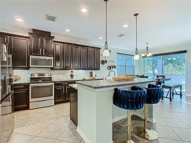 a kitchen with stainless steel appliances granite countertop a sink a stove and a wooden floors