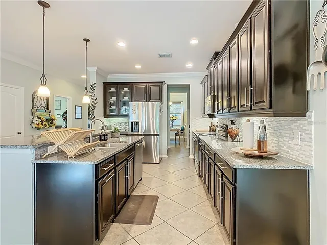 a kitchen with stainless steel appliances granite countertop a sink a stove a refrigerator and chairs