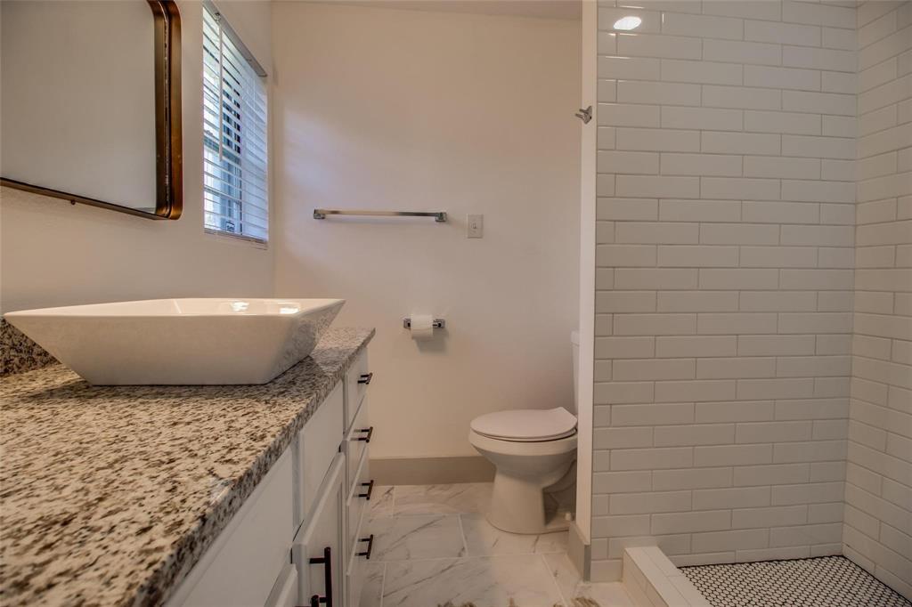 702 Ridgedale Drive Garland, TX 75041 - Photo 16 of 23 a bathroom with a granite countertop toilet and a sink