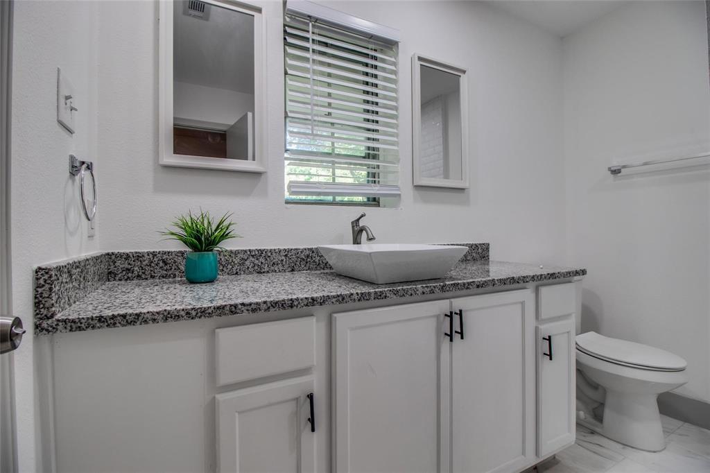 702 Ridgedale Drive Garland, TX 75041 - Photo 17 of 23 a kitchen with a granite countertop sink a toilet and a mirror