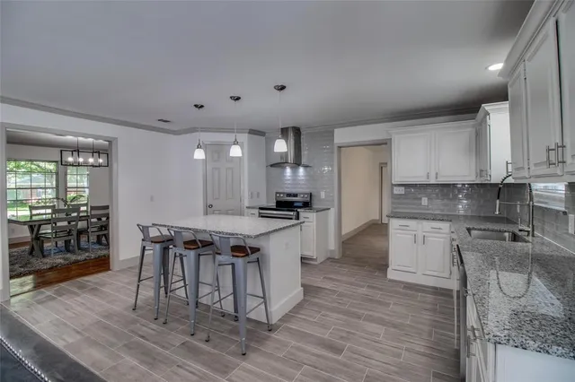 a kitchen with stainless steel appliances granite countertop a stove a refrigerator a sink a dining table and chairs with wooden floor