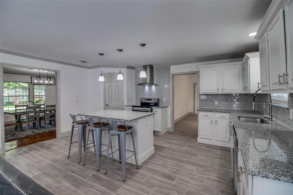 702 Ridgedale Drive Garland, TX 75041 - Photo 8 of 23 a kitchen with stainless steel appliances granite countertop a stove a refrigerator a sink a dining table and chairs with wooden floor