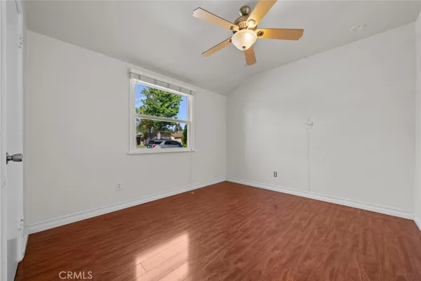 an empty room with wooden floor fan and windows