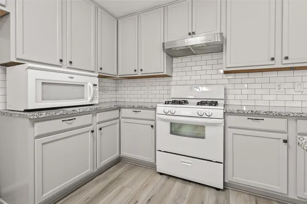 a kitchen with white cabinets and white appliances