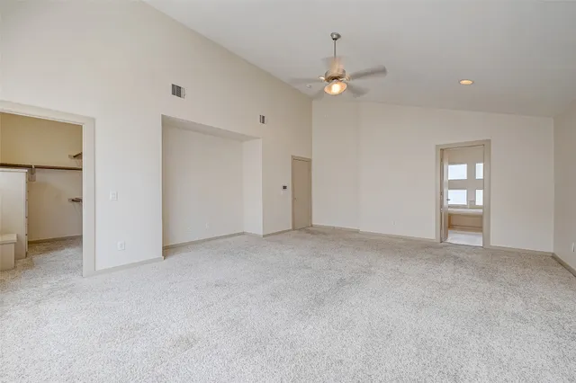 an empty room with windows and ceiling fan