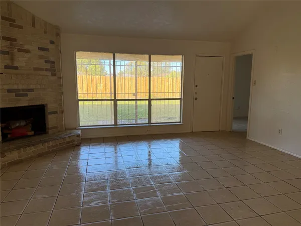 a view of an empty room with a fireplace and a window