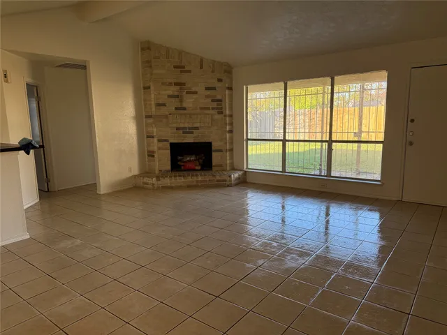 an empty room with windows and fireplace