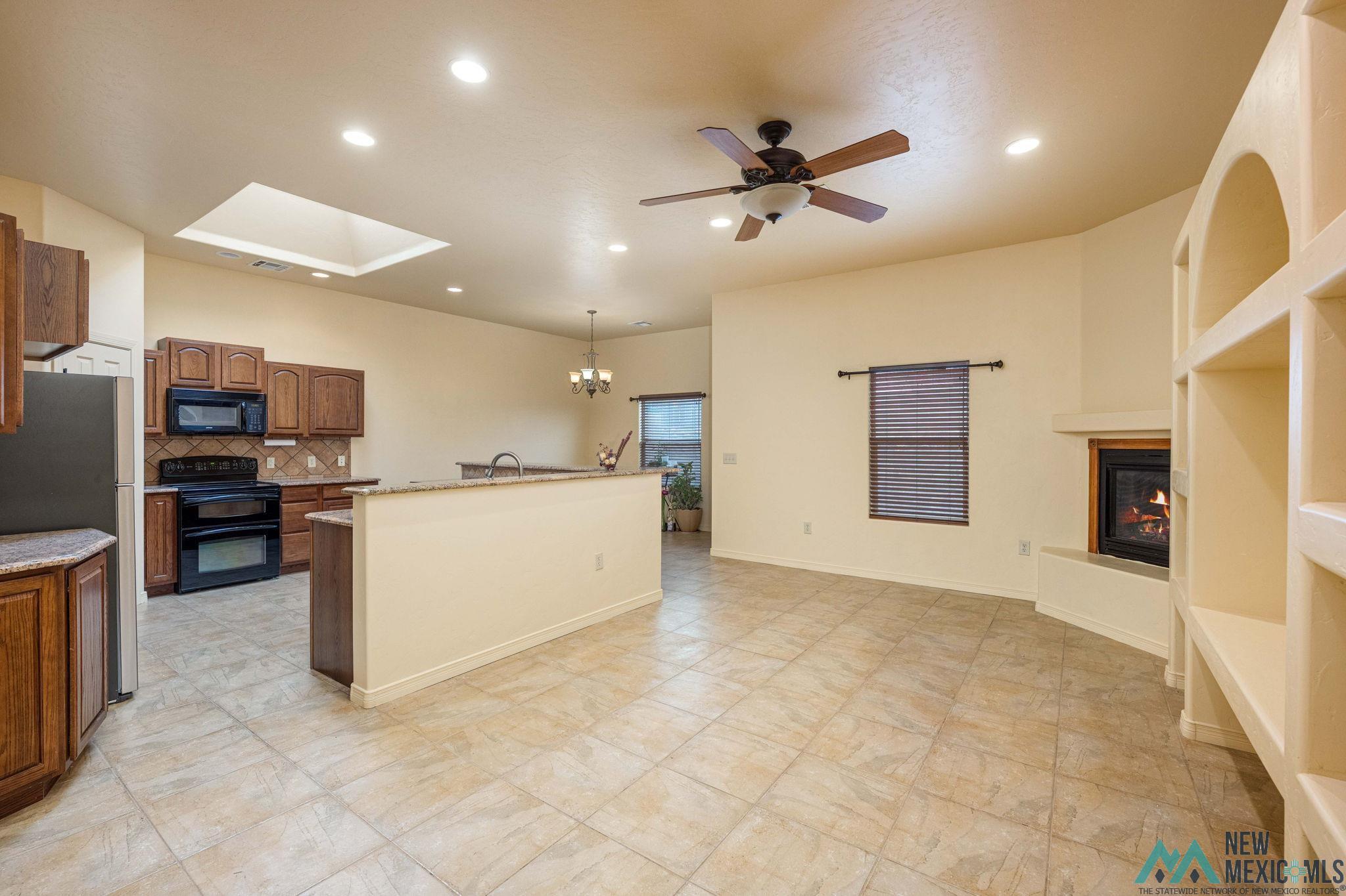 3884 Adriatic Road Las Cruces, NM 88012 - Photo 8 of 45 Open-concept living space featuring ceramic tile flooring, a corner fireplace with a mantel, and built-in arched shelving