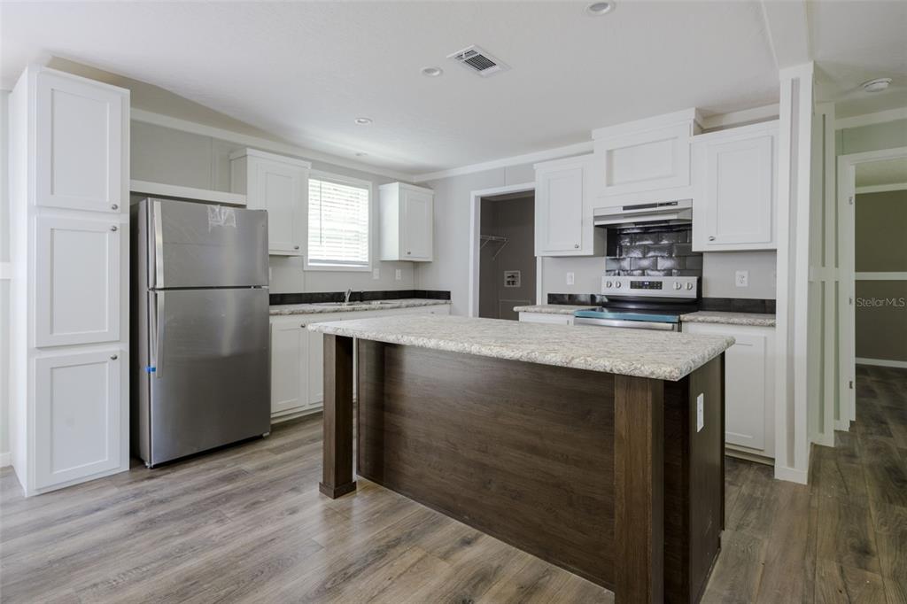 374 Sisco Road Pomona Park, FL 32181 - Photo 9 of 40 a kitchen with kitchen island granite countertop a refrigerator stove and microwave