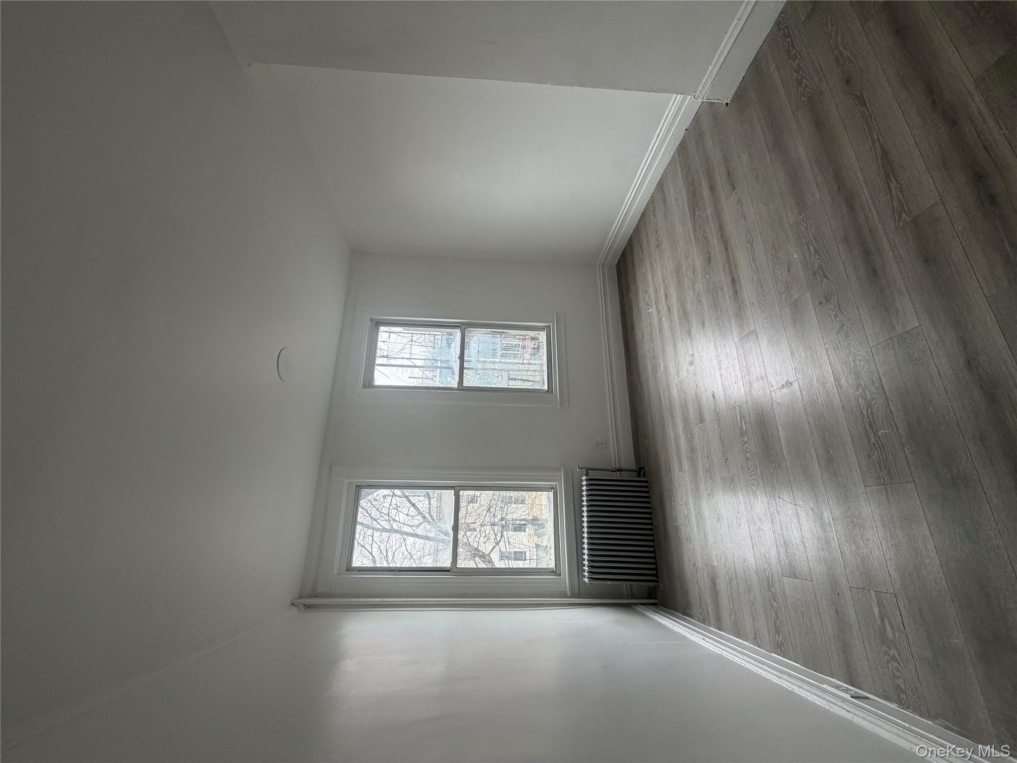 88 Cornelia Street Brooklyn, NY 11221 - Photo 3 of 8 an empty room with wooden floor and windows
