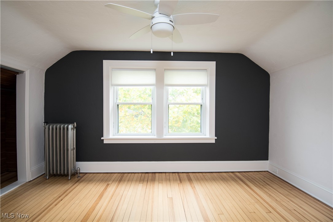 7003 Brecksville Road Independence, OH 44131 - Photo 9 of 35 Additional living space with light wood finished floors, radiator heating unit, vaulted ceiling, and ceiling fan