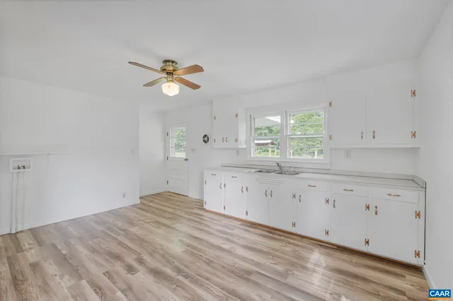 a kitchen with granite countertop a stove a sink and white cabinets with wooden floor