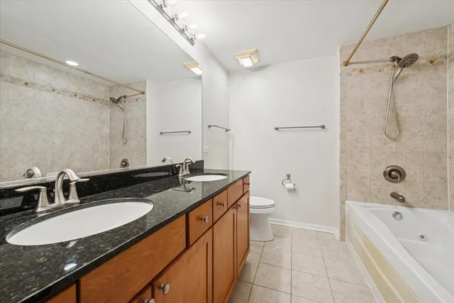 a bathroom with a granite countertop double vanity sink and mirror with shower