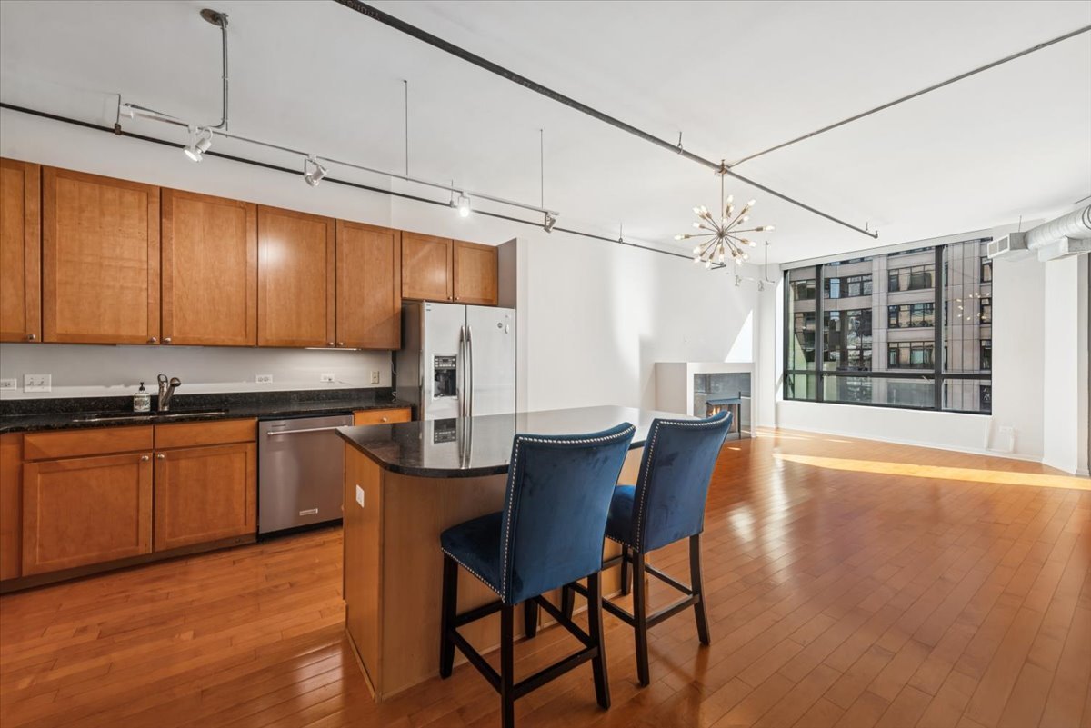 520 South State Street, Unit 907 Chicago, IL 60605 - Photo 4 of 26 a kitchen with stainless steel appliances kitchen island granite countertop a table chairs in it and wooden floors