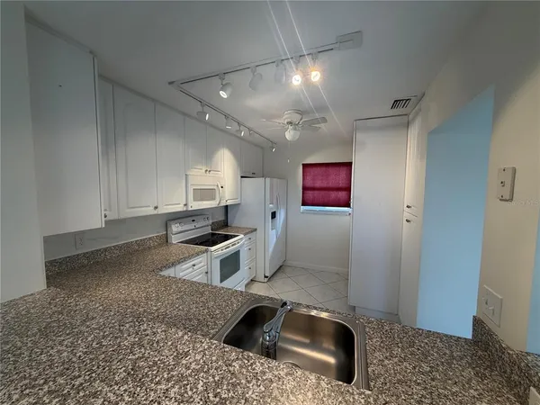 a kitchen with granite countertop a sink a stove and cabinets