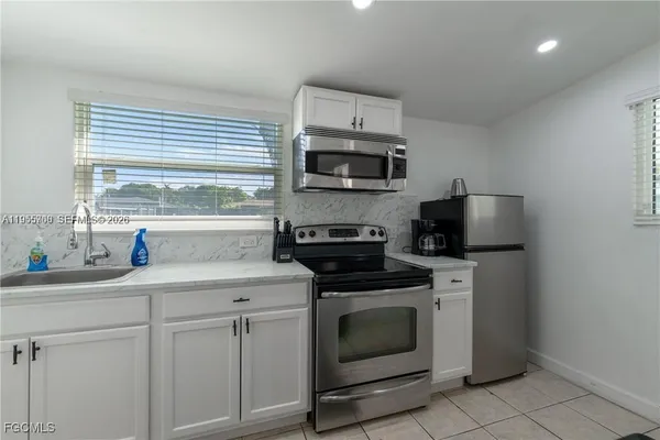 a kitchen with granite countertop white cabinets sink and stainless steel appliances