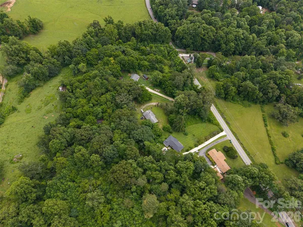 an aerial view of a house with pool outdoor space and trees all around