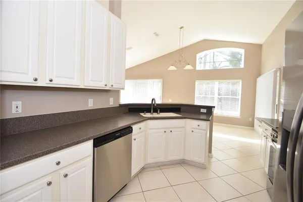 a kitchen with granite countertop white cabinets white appliances with a sink and a window