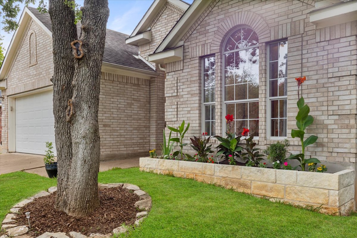 9012 Meacham Way Austin, TX 78749 - Photo 2 of 34 Brick exterior featuring a stone planter with diverse foliage