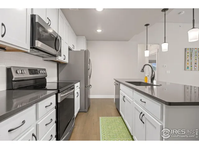 a kitchen with stainless steel appliances granite countertop a sink a stove and a refrigerator