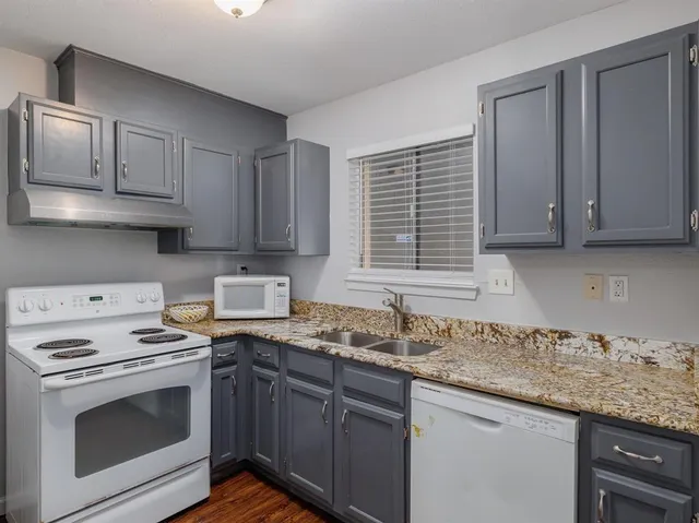 a kitchen with granite countertop white cabinets and white appliances