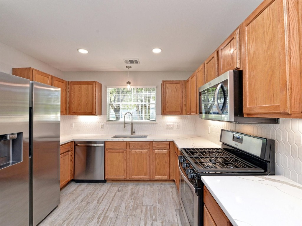 17816 Cutback Drive Manor, TX 78653 - Photo 4 of 28 a kitchen with stainless steel appliances granite countertop a stove a sink dishwasher and a refrigerator