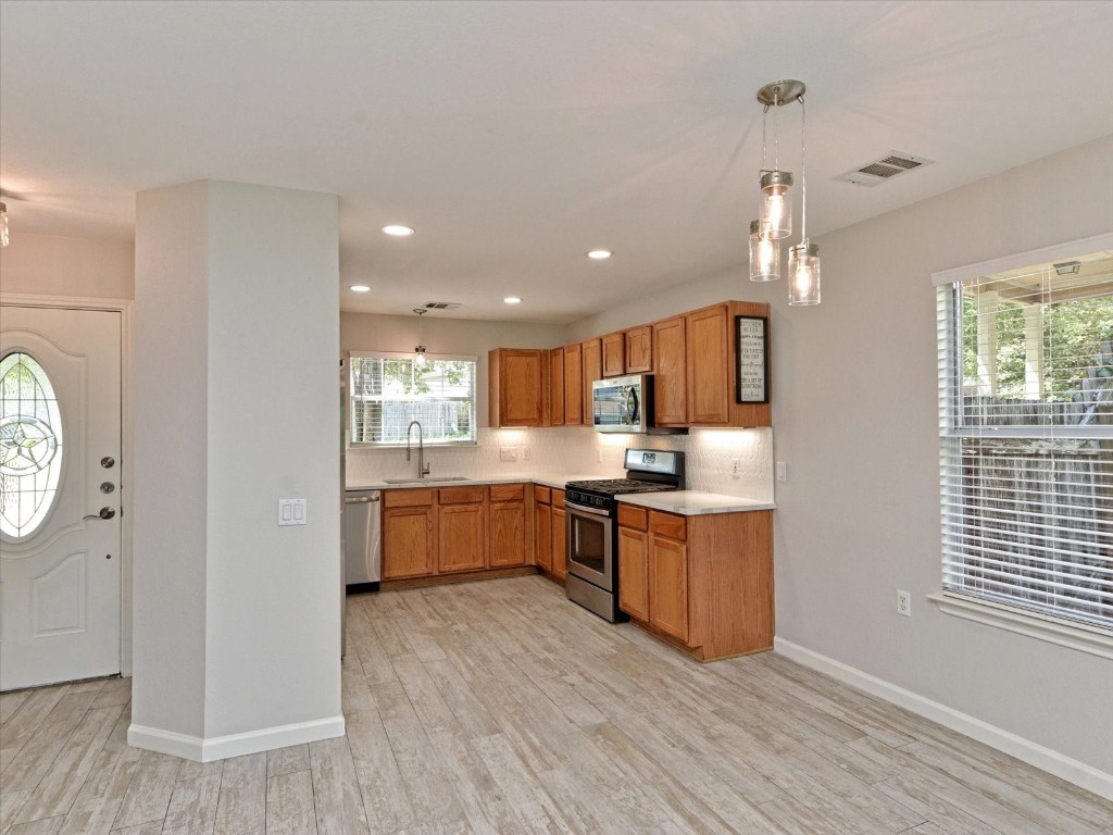 17816 Cutback Drive Manor, TX 78653 - Photo 10 of 28 a large kitchen with a wooden floor and stainless steel appliances