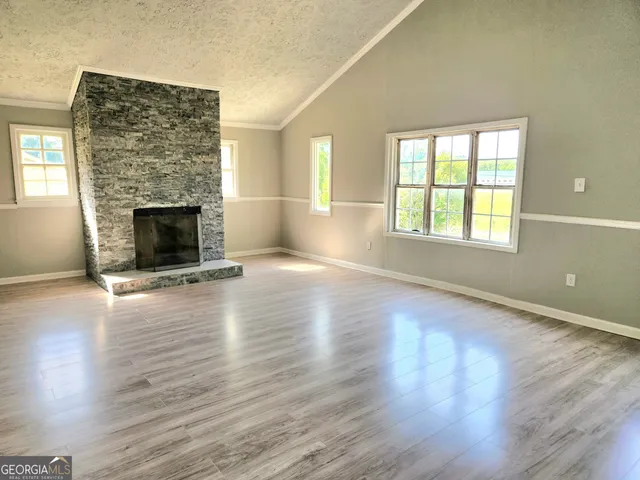 an empty room with wooden floor fireplace and windows