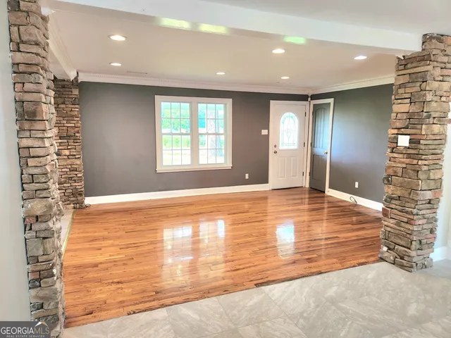 a view of an empty room with window and wooden floor